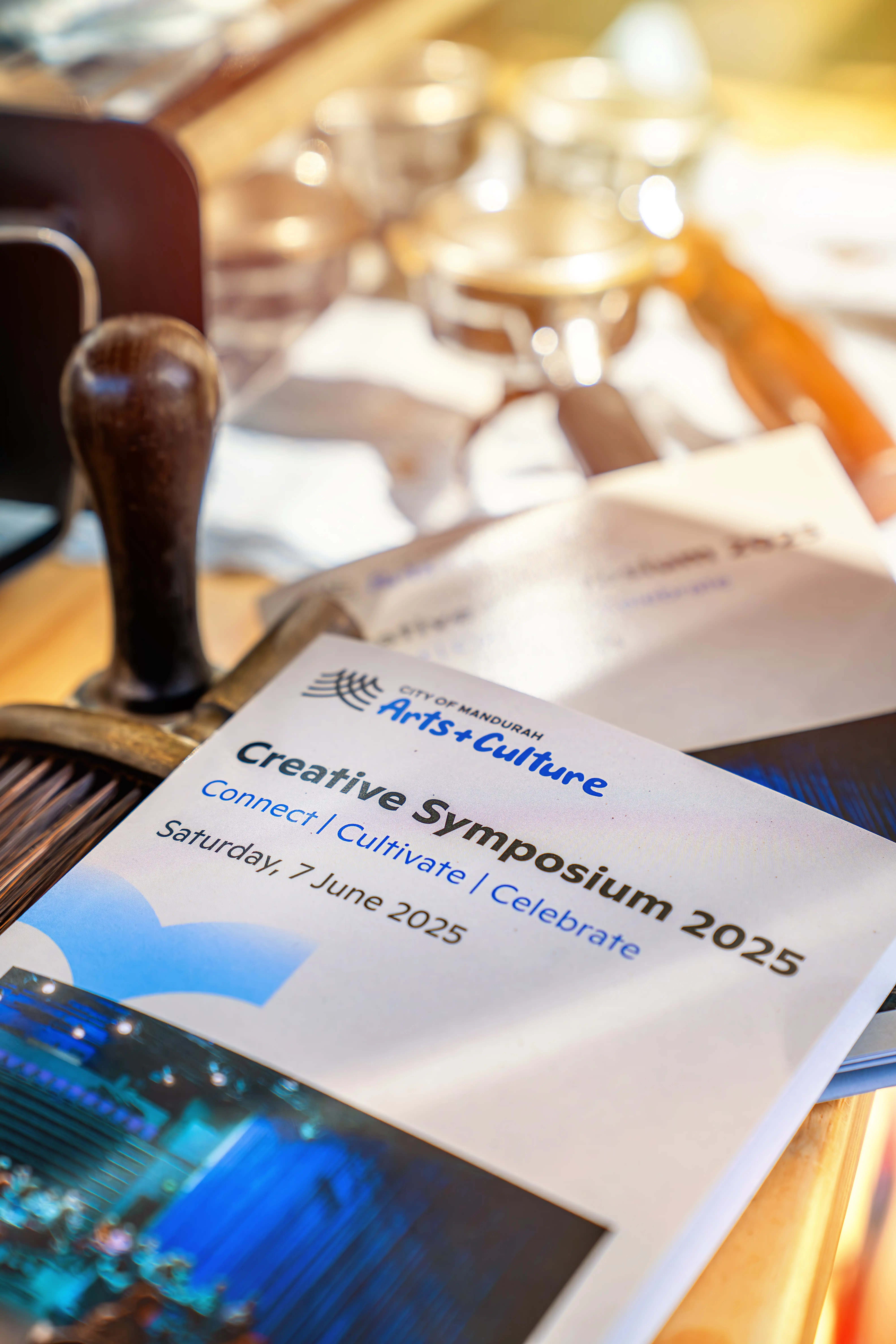 Close-up of a Creative Symposium 2025 booklet on a table with other materials.